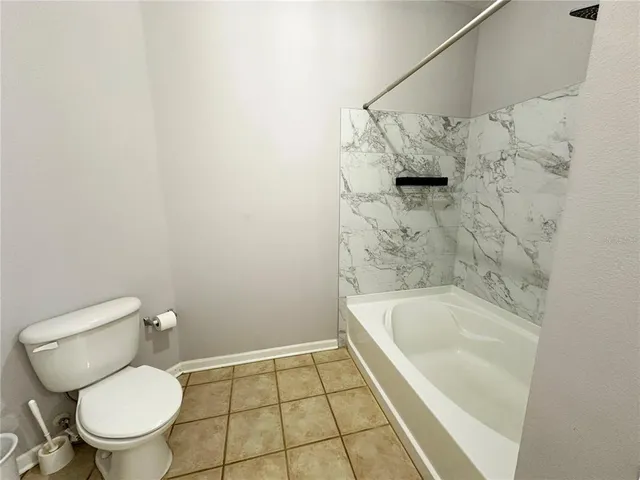 a white toilet sitting next to a bath tub and a shower