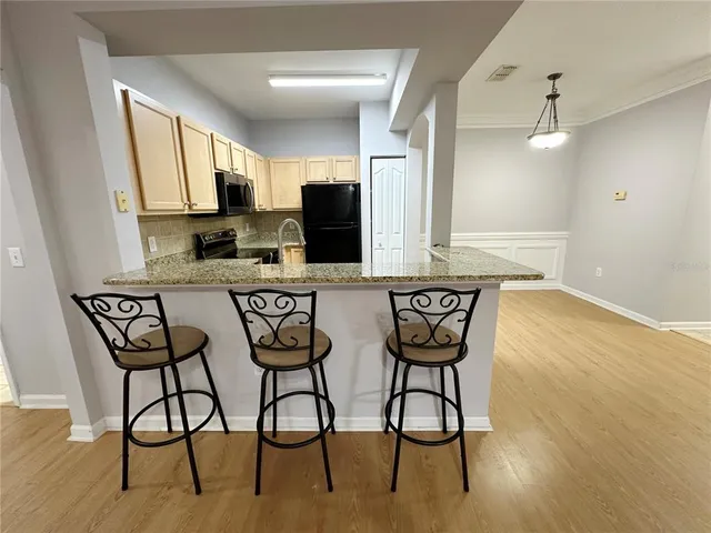 a kitchen with stainless steel appliances kitchen island granite countertop a table chairs in it and wooden floors