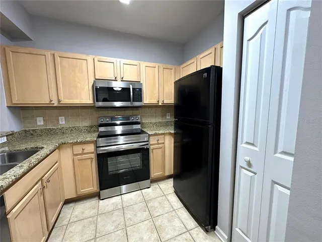 a kitchen with granite countertop a refrigerator stove and microwave