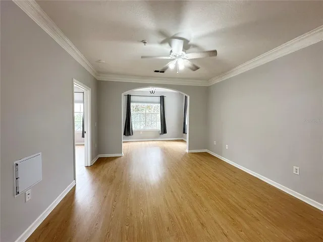 an empty room with wooden floor chandelier fan and windows