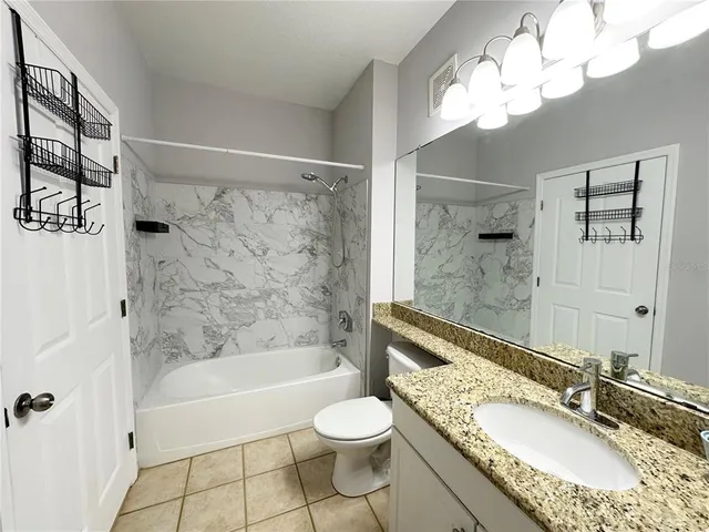 a bathroom with a granite countertop sink a toilet tub and shower