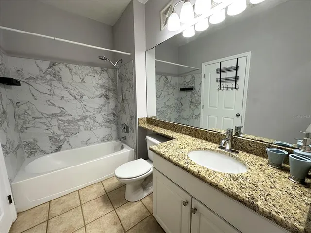 a bathroom with a granite countertop sink a mirror a bathtub and a toilet