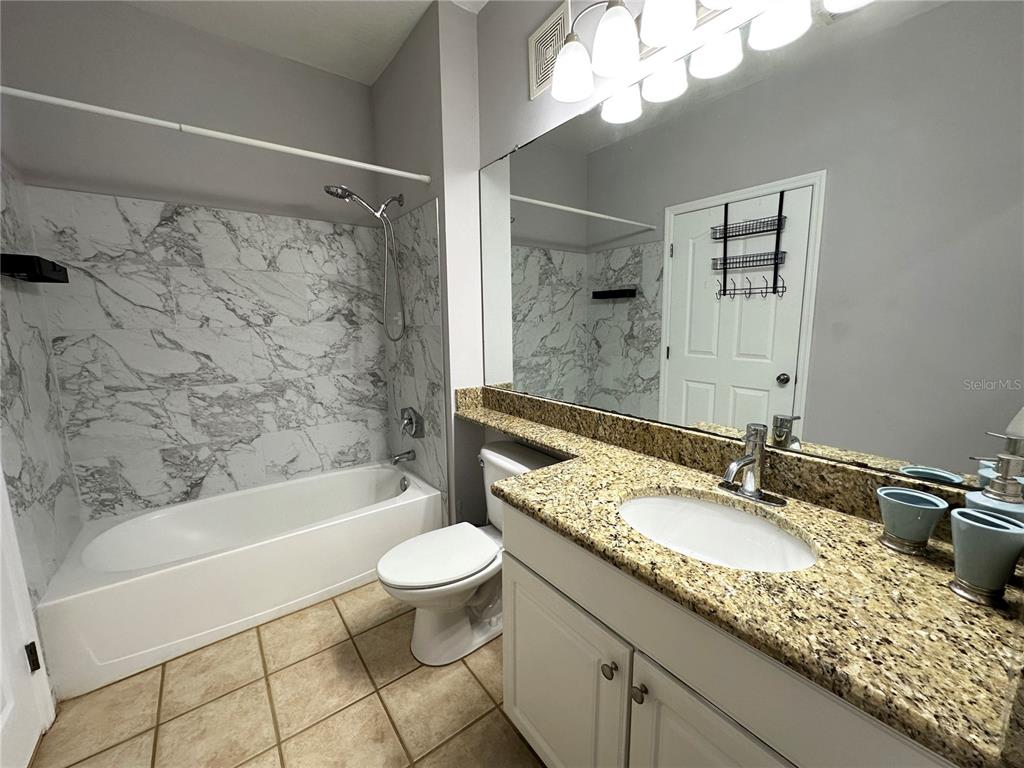 12843 Madison Pointe Circle, Unit 201 Orlando, FL 32821 - Photo 9 of 53 a bathroom with a granite countertop sink a mirror a bathtub and a toilet