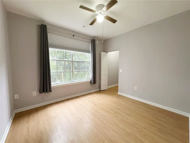 a view of an empty room with a window and wooden floor