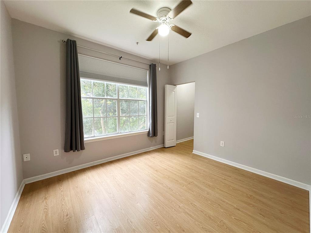 12843 Madison Pointe Circle, Unit 201 Orlando, FL 32821 - Photo 10 of 53 a view of an empty room with a window and wooden floor