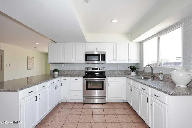 a kitchen with stainless steel appliances granite countertop a sink and dishwasher a stove top oven with white cabinets
