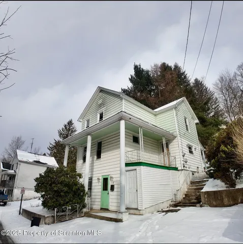 a view of a white house with large windows and plants