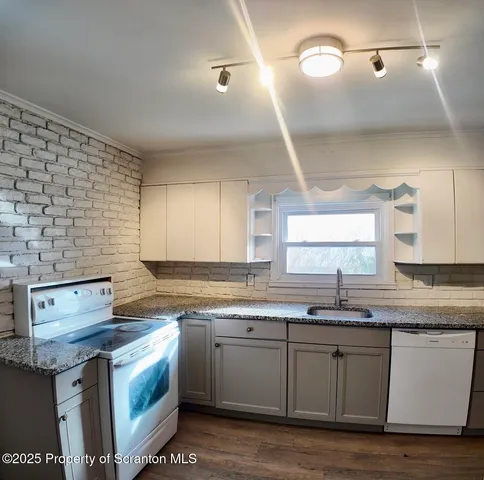 a kitchen with granite countertop a sink cabinets and stainless steel appliances
