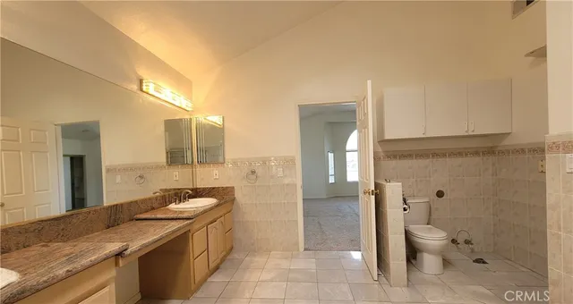 a bathroom with a granite countertop sink a toilet a mirror and shower