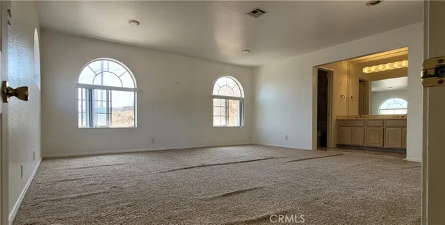 an empty room with windows and chandelier fan