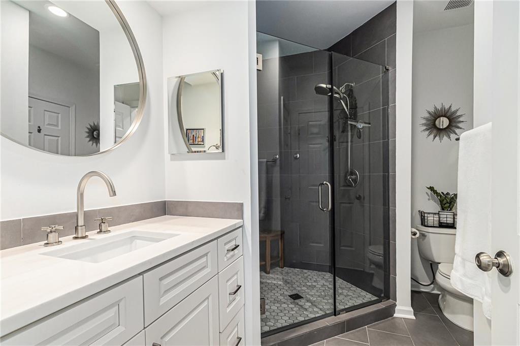 220 Renaissance Parkway Northeast, Unit 1211 Atlanta, GA 30308 - Photo 17 of 24 a bathroom with a shower sink and mirror