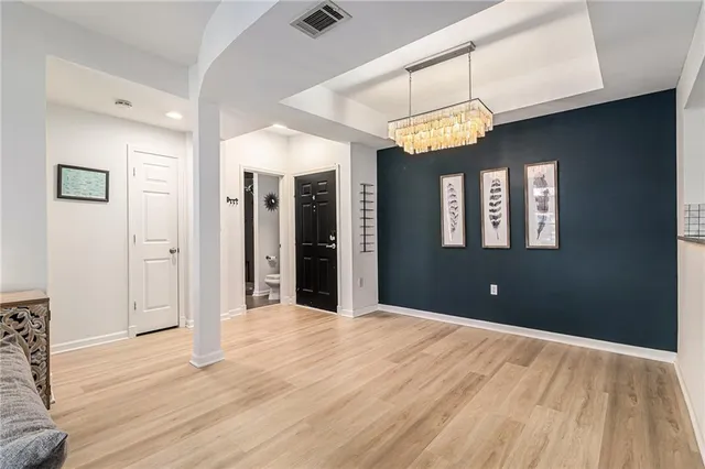 a view of an empty room with a chandelier fan and a bathroom