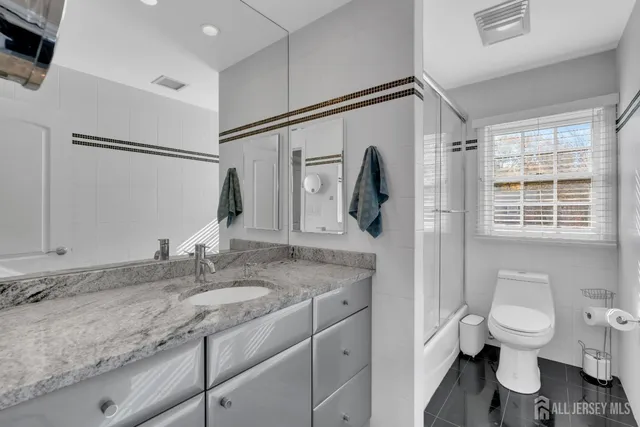 a bathroom with a granite countertop sink toilet and shower