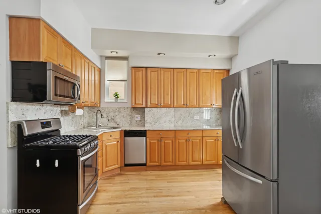 a kitchen with stainless steel appliances granite countertop a refrigerator and a stove top oven