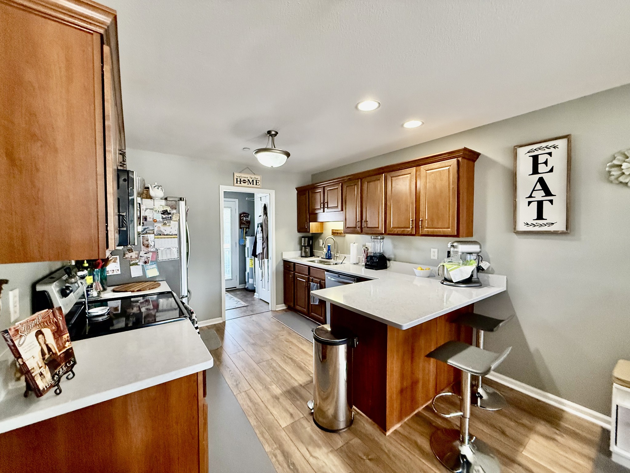 233 Winfrey Court Pleasant View, TN 37146 - Photo 12 of 28 a view of a kitchen with kitchen island a stove a refrigerator a sink dishwasher with a dining table and chair with wooden floor