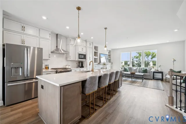 a large kitchen with kitchen island a stove a sink a center island and wooden floor