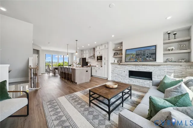 a kitchen with stainless steel appliances kitchen island granite countertop a stove a refrigerator a sink a dining table and chairs with wooden floor