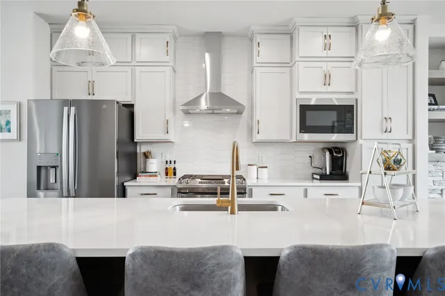 a kitchen with stainless steel appliances a stove a sink a center island and a wooden floor