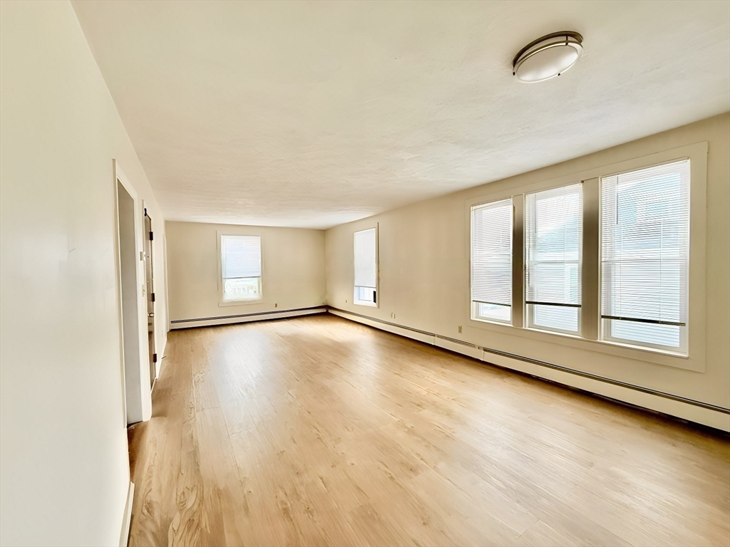 17 Maple Street, Unit 2 Braintree, MA 02184 - Photo 3 of 25 an empty room with wooden floor and windows