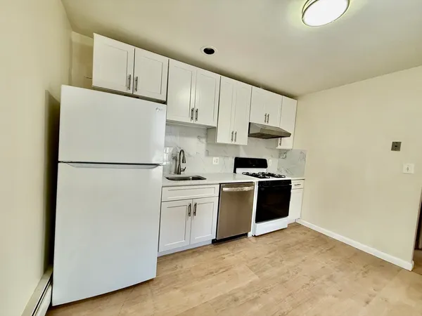a kitchen with stainless steel appliances granite countertop a stove a refrigerator and white cabinets