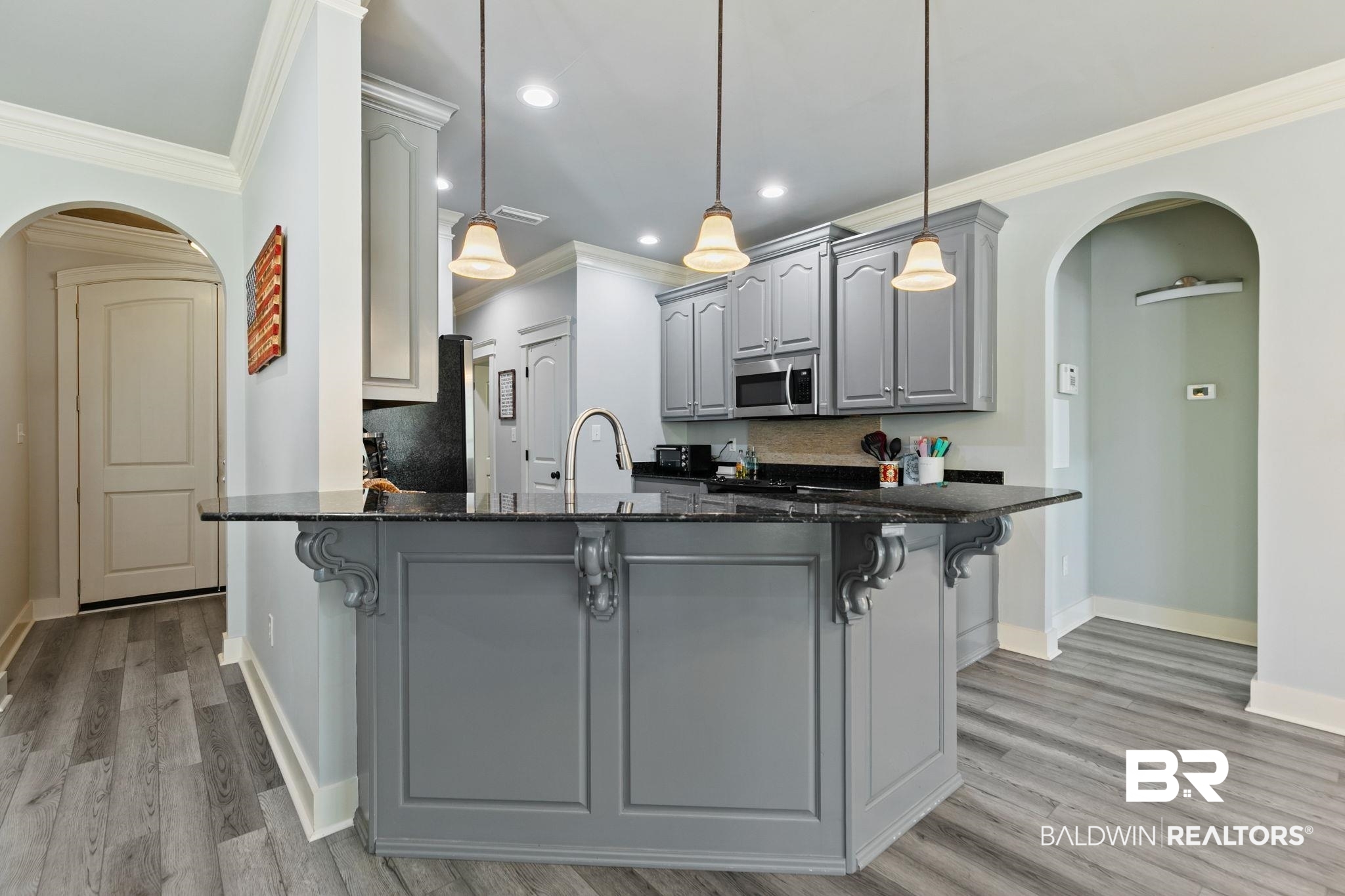9584 Sanibel Loop Daphne, AL 36526 - Photo 15 of 48 Kitchen with arched walkways, gray cabinets, dark stone counters, a peninsula, and light wood-style flooring