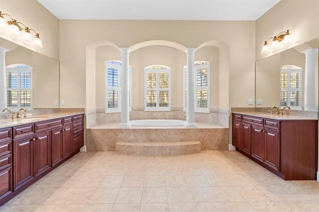 a spacious bathroom with a granite countertop tub a double vanity sink and a large mirror