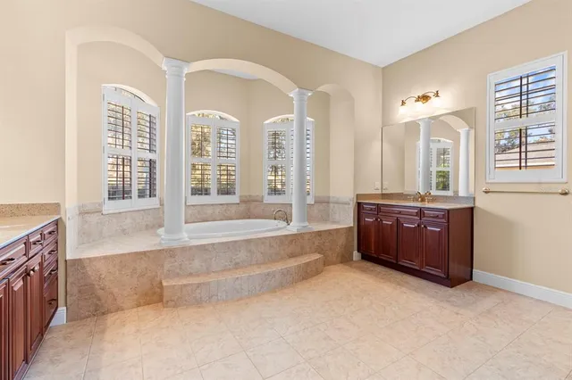a spacious bathroom with a tub sink and mirror