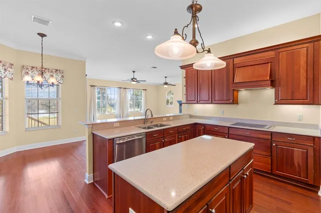 a kitchen with a stove a sink dishwasher a kitchen island with wooden cabinets and floor