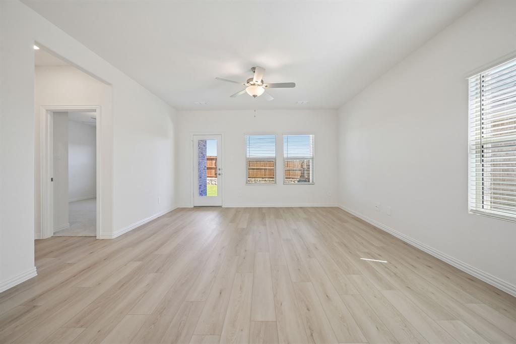 1705 Arches Road Anna, TX 75409 - Photo 13 of 33 an empty room with wooden floor chandelier fan and windows