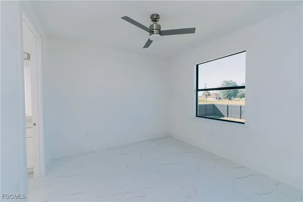 an empty room with windows and ceiling fan
