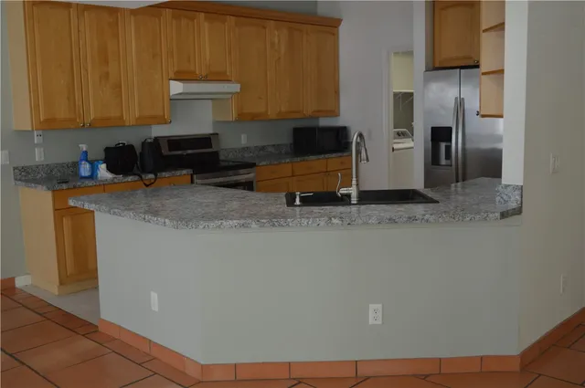 a kitchen with stainless steel appliances granite countertop a refrigerator a stove and a sink