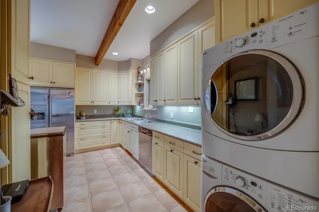a kitchen with stainless steel appliances granite countertop a sink a stove a washer and dryer