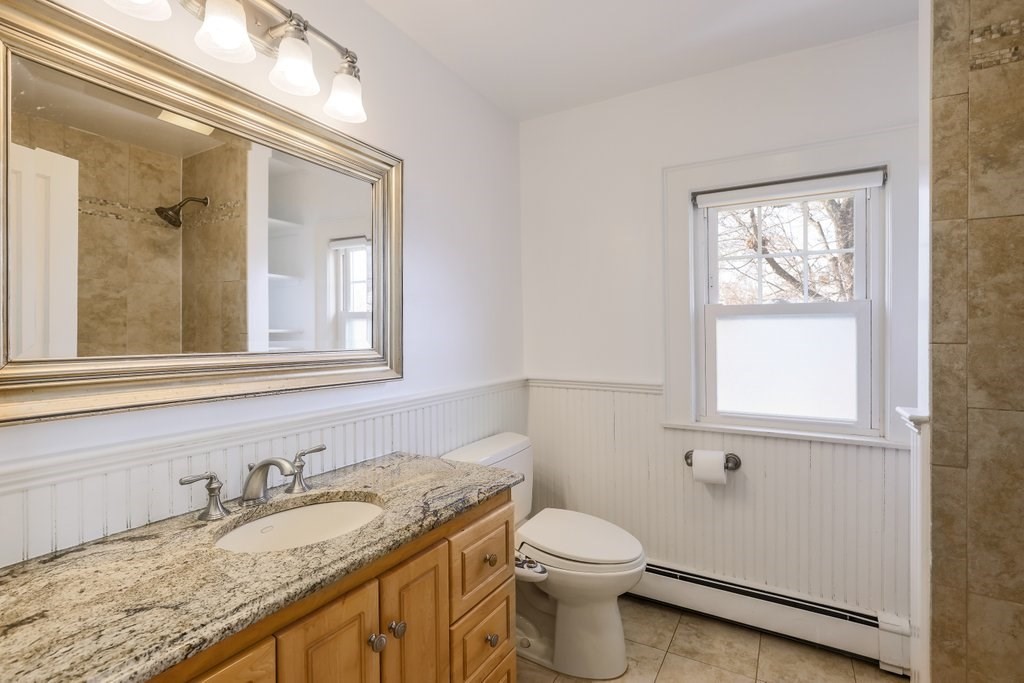 8 Smith Avenue Reading, MA 01867 - Photo 17 of 32 a bathroom with a granite countertop toilet a sink and mirror