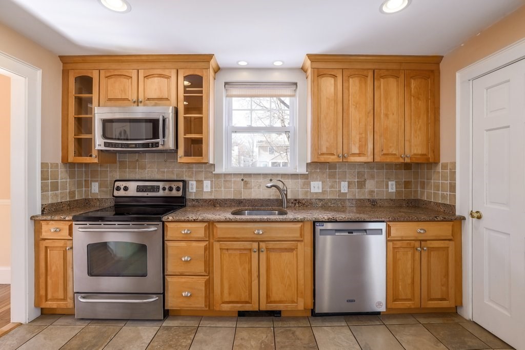 8 Smith Avenue Reading, MA 01867 - Photo 7 of 32 a kitchen with granite countertop a stove top oven microwave and cabinets