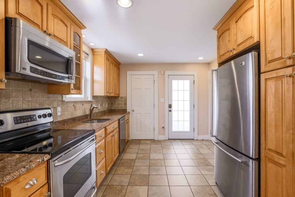 8 Smith Avenue Reading, MA 01867 - Photo 9 of 32 a kitchen with a refrigerator a stove top oven and a sink