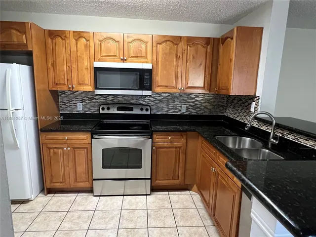 a kitchen with granite countertop a stove sink and microwave