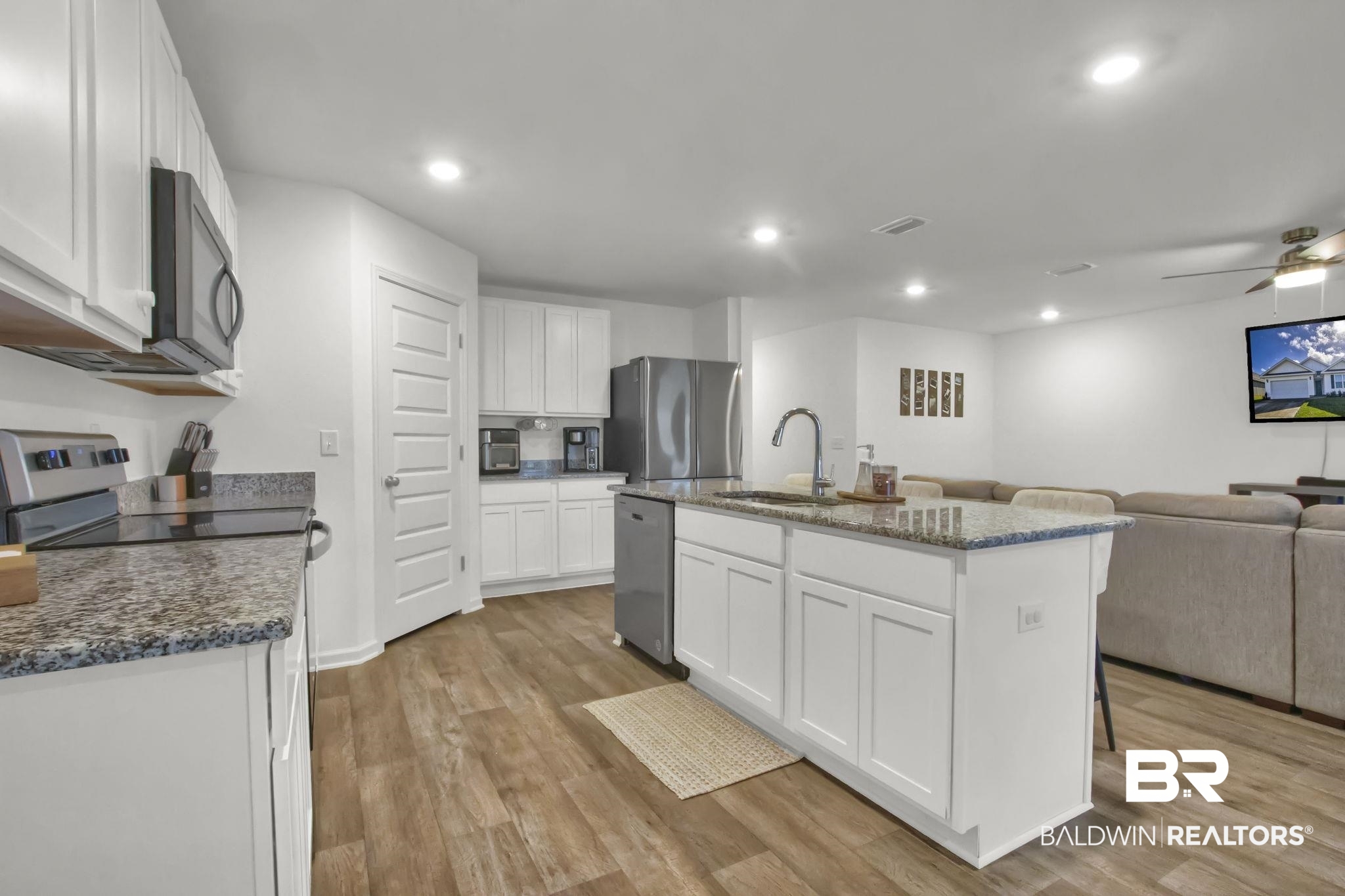 23810 Unbridled Loop Daphne, AL 36526 - Photo 11 of 50 Kitchen with a center island with sink, appliances with stainless steel finishes, ceiling fan, light wood-type flooring, and white cabinets