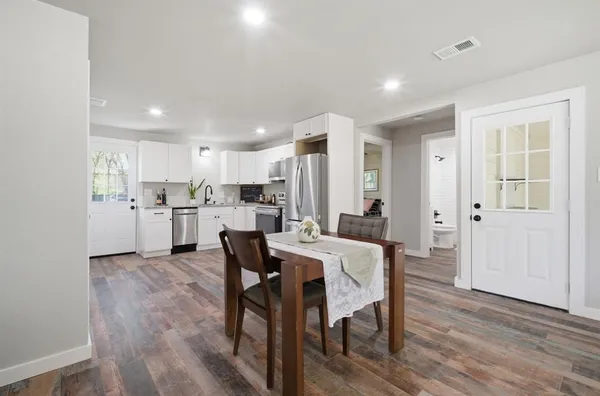 a kitchen with a dining table chairs refrigerator wooden cabinets and wooden floor