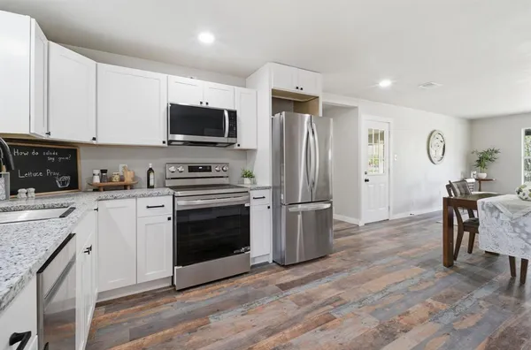 a kitchen with a refrigerator stove and wooden floor