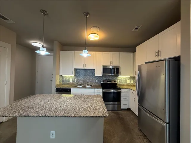 a kitchen with stainless steel appliances granite countertop a refrigerator a stove a sink and a refrigerator