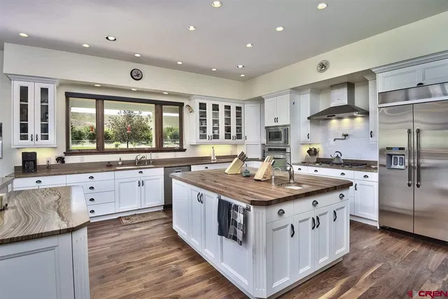 a kitchen with stainless steel appliances granite countertop a stove top oven a refrigerator a sink and dishwasher with wooden floor