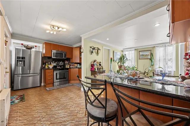 a kitchen with stainless steel appliances kitchen island granite countertop a refrigerator and a stove top oven