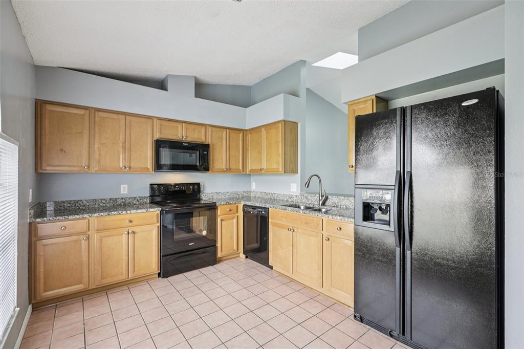 734 Bittern Lane Kissimmee, FL 34759 - Photo 15 of 55 a kitchen with stainless steel appliances granite countertop a refrigerator and a stove top oven