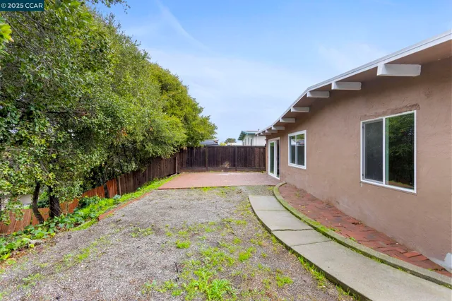 a view of a backyard with wooden fence and trees