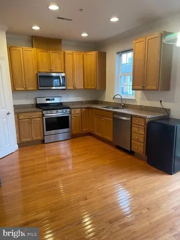 a view of an empty room with wooden floor and windows