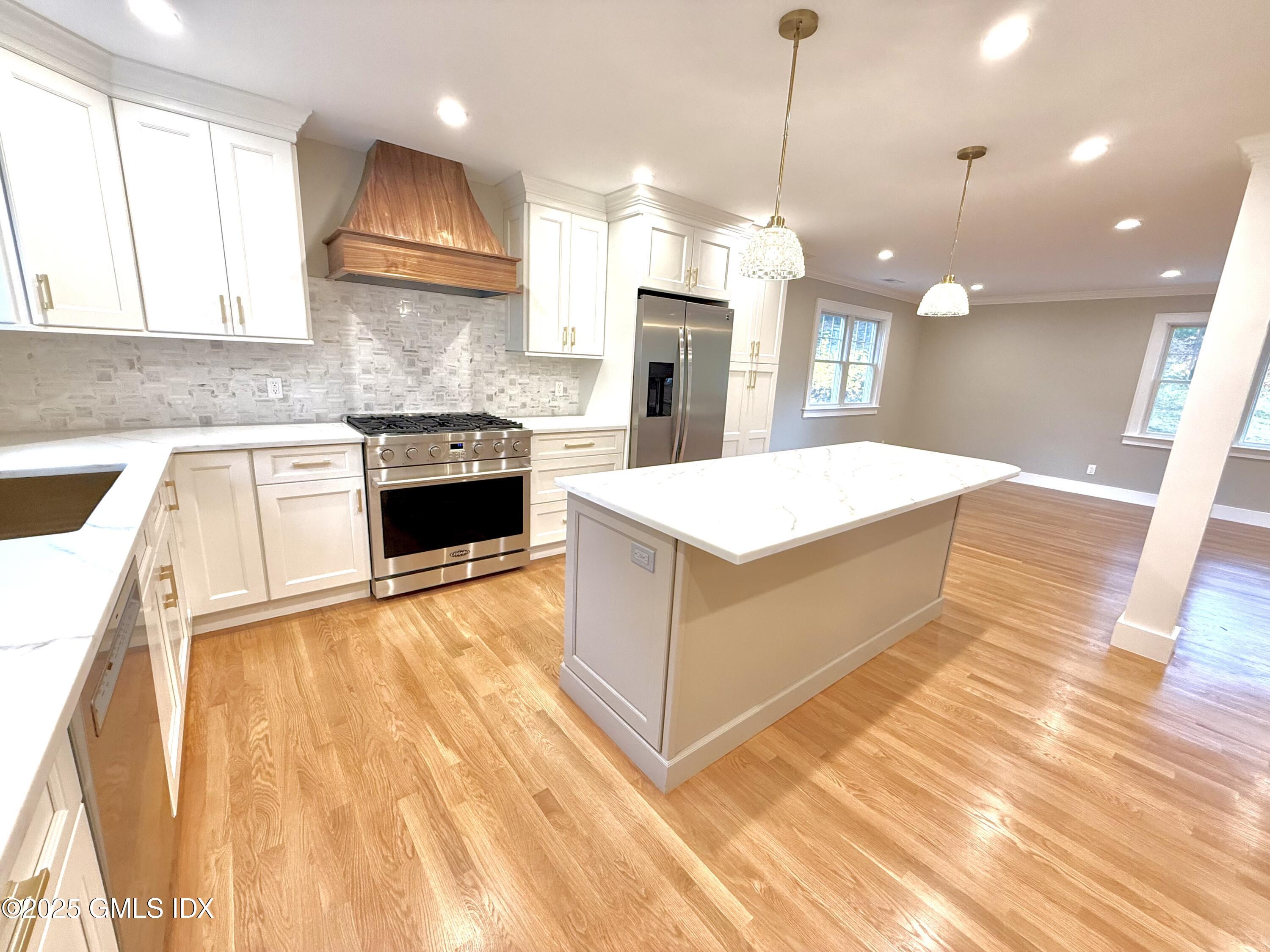 a large kitchen with kitchen island a stove a sink a center island and wooden floor