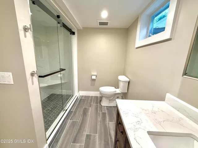 a bathroom with a granite countertop sink a toilet and shower