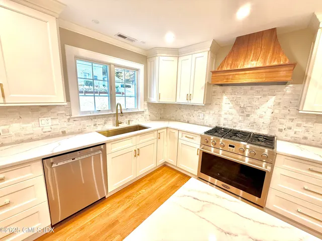 a kitchen with granite countertop a sink cabinets stainless steel appliances and a window