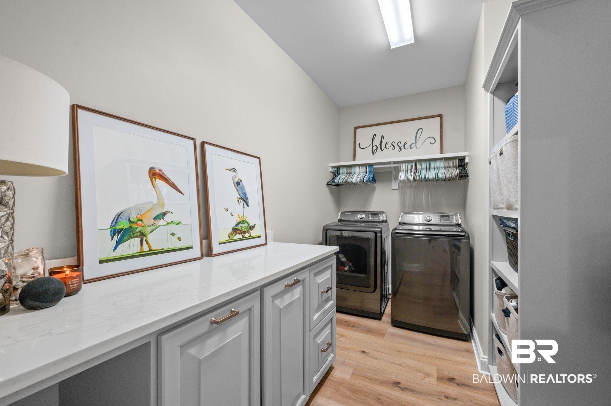 409 Fortune Drive Fairhope, AL 36532 - Photo 33 of 42 Dedicated laundry area featuring a white countertop, light gray cabinetry with gold-tone hardware, wood-finish flooring, and built-in shelving