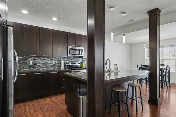 a kitchen with stainless steel appliances granite countertop a refrigerator a stove a sink a dining table and chairs